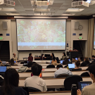 A view from the back of the lecture hall of students facing the four panelists.